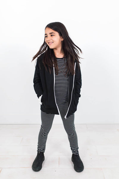 Girl wearing black and white stripe leggings and top.  Organic cotton hoodie.  Designed for capsule collections.