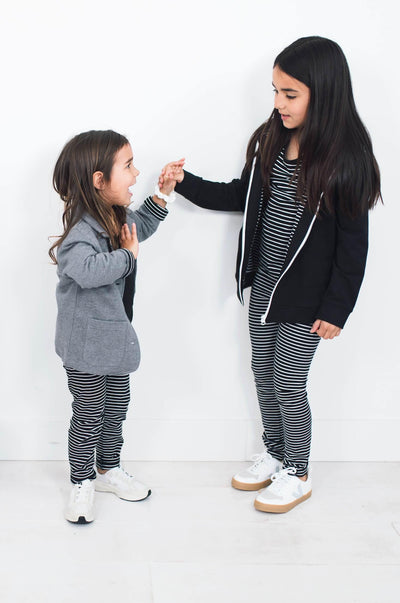 Two girls wearing black and white striped leggings made from organic cotton.  Perfect for capsule wardrobes.