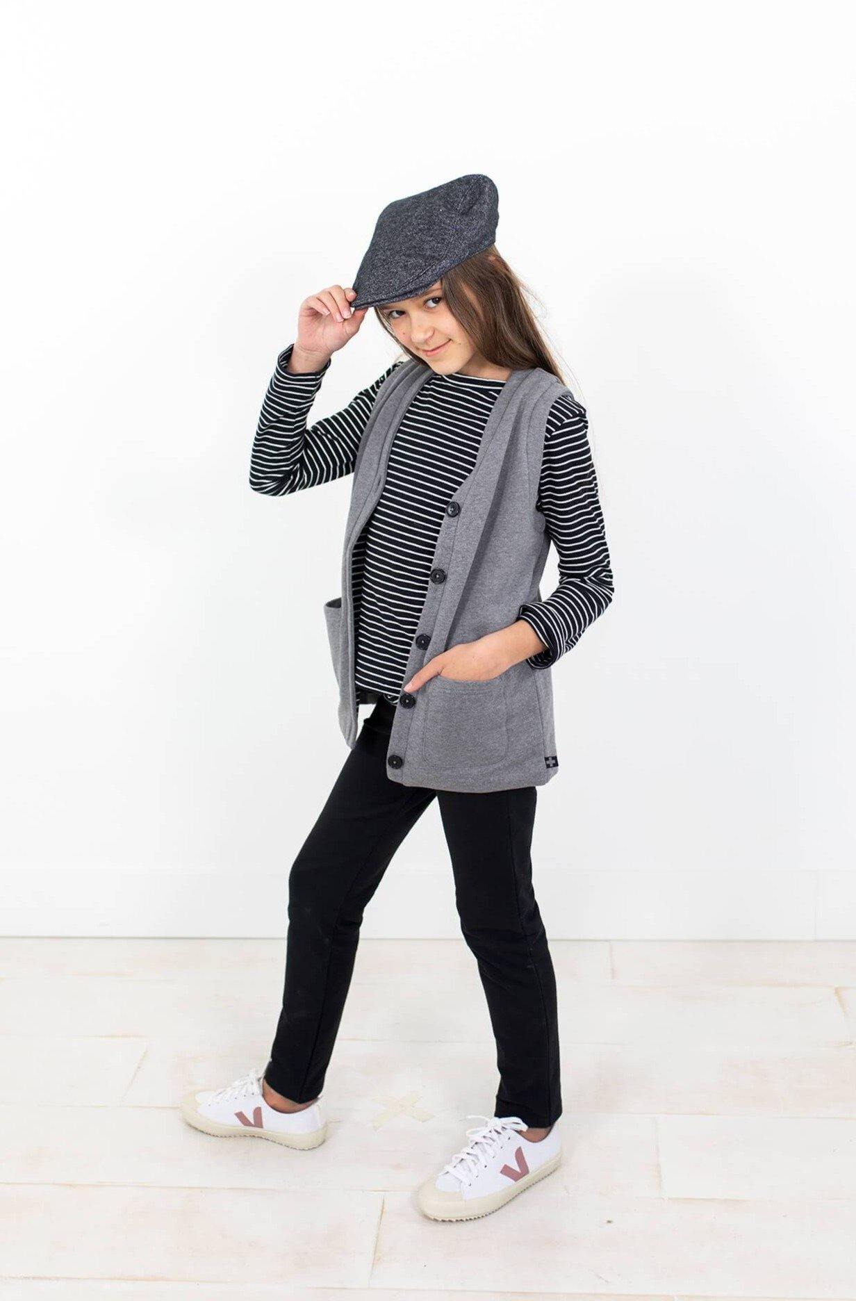 Girl wearing organic cotton long sleeve top.  Black with white stripes.  Grey vest outer.  Made from organic cotton.