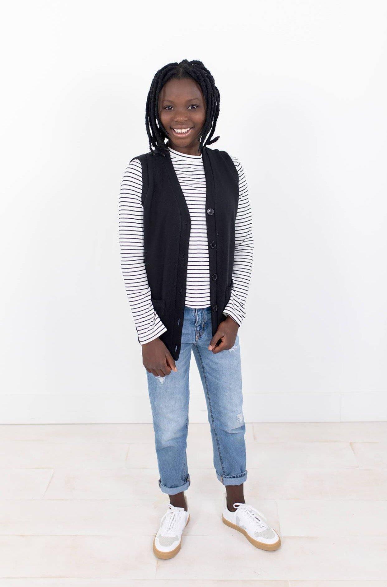 Girl wearing 100% organic cotton long sleeve tee; white with stripes, curved hem. Kids sizes 5-12. Minimalist design for kids' capsule wardrobe. Ethically made by a fair trade certified manufacturer.