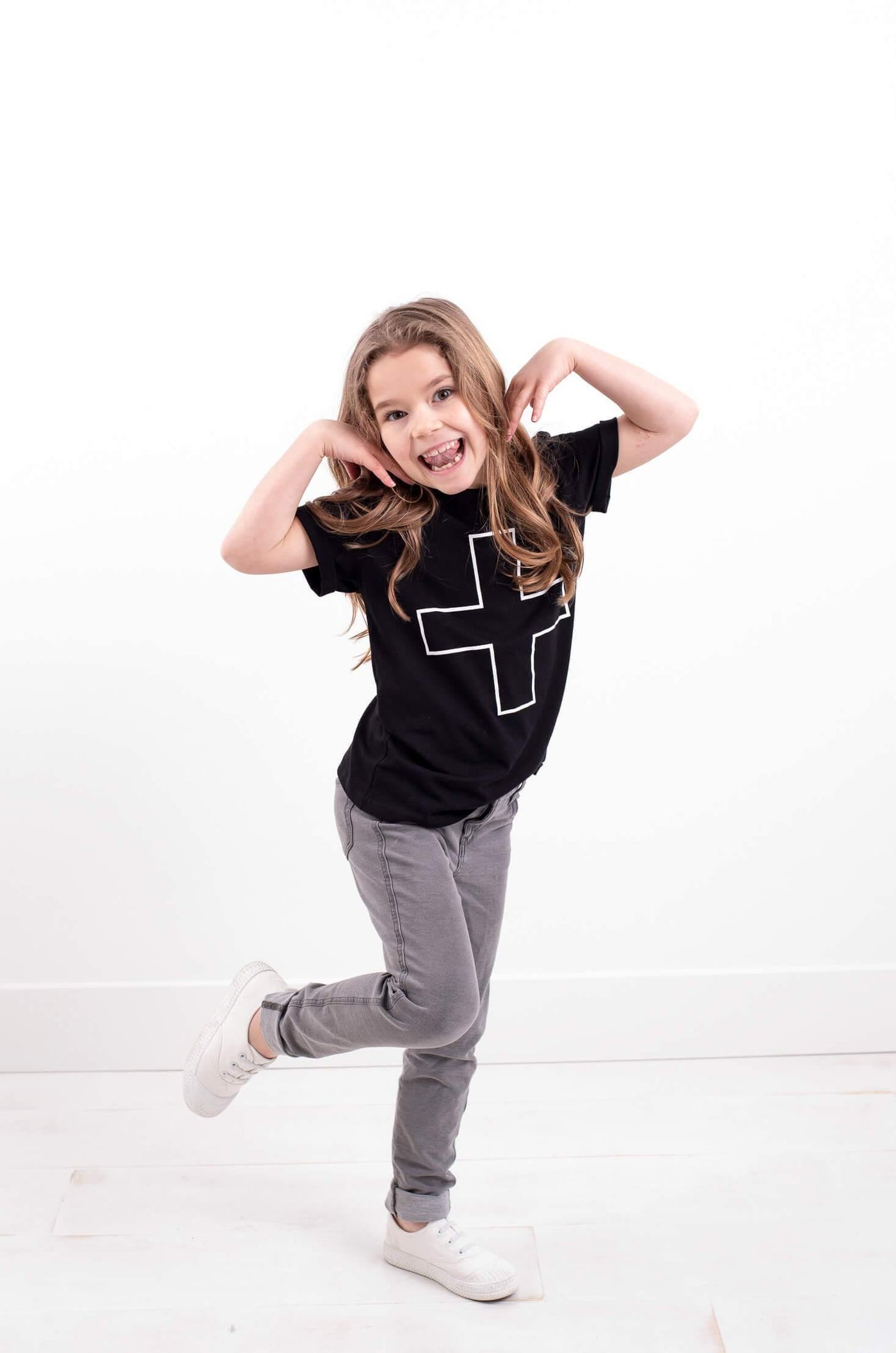 Girl wearing black organic cotton tee with plus sign.  Ethically made designed in Canada.