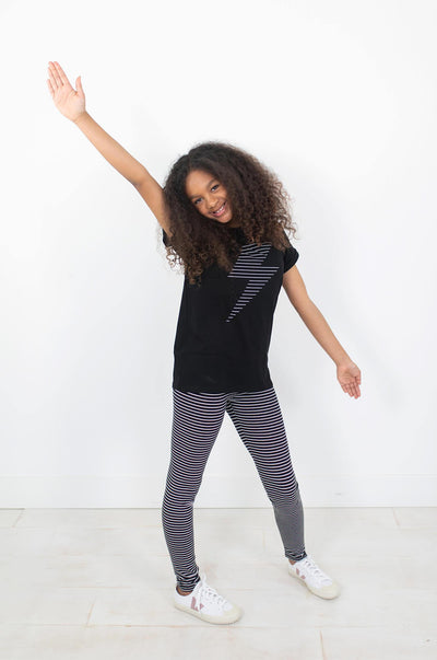 Girl wearing white and black stripe leggings.  Ethically made with organic cotton.