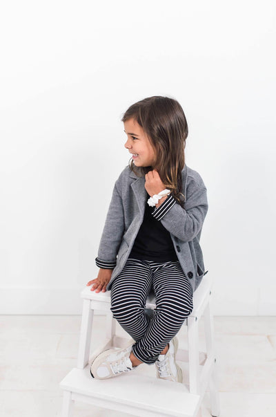 Sitting girl wearing grey organic cotton blazer.