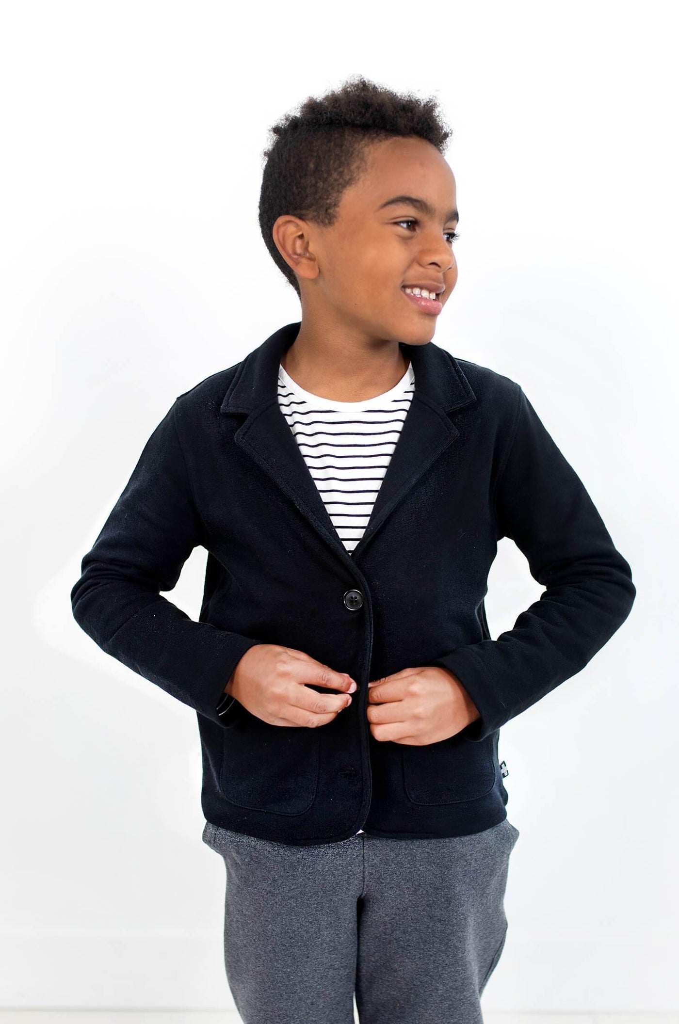 Smiling boy wearing black blazer made from organic cotton.