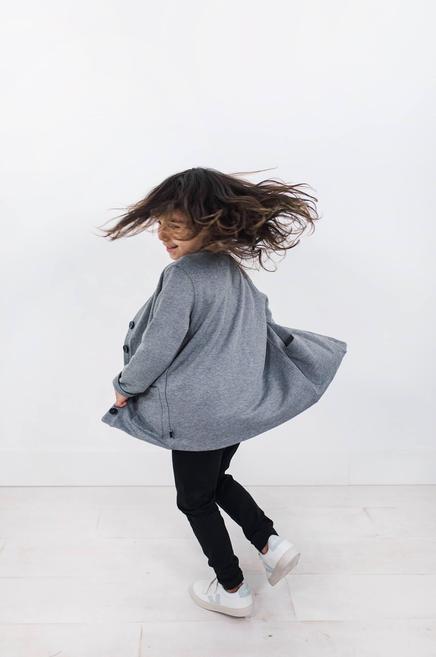 Girl wearing light grey cardigan.  Made from organic cotton.  Designed in Canada.