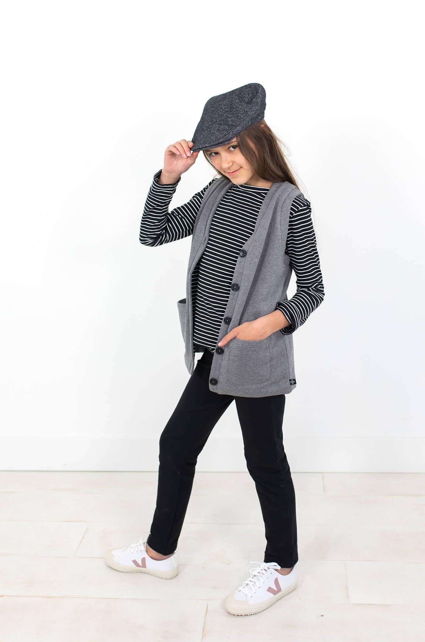 Girl wearing grey organic cotton vest and grey hat.