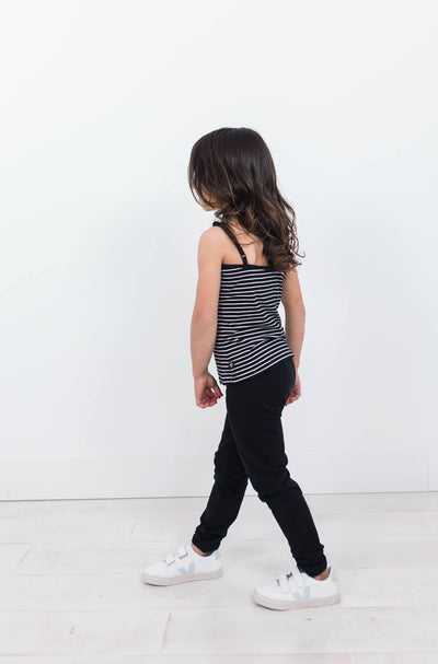Girl wearing black organic cotton legging.  Striped cami and white shoes.